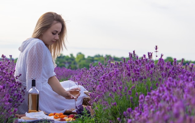 A girl holds a glass of white wine against the backdrop of a lavender field A girl drinks wine in a lavender field