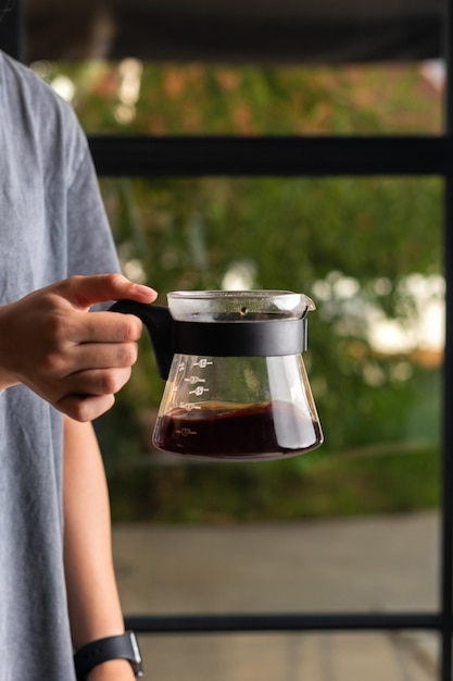 The girl holds in her hand a glass pot of hot filtered coffee