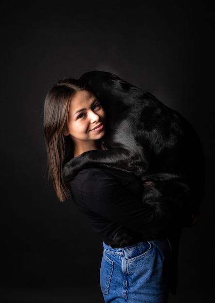 A girl holds a Labrador Retriever dog in her arms