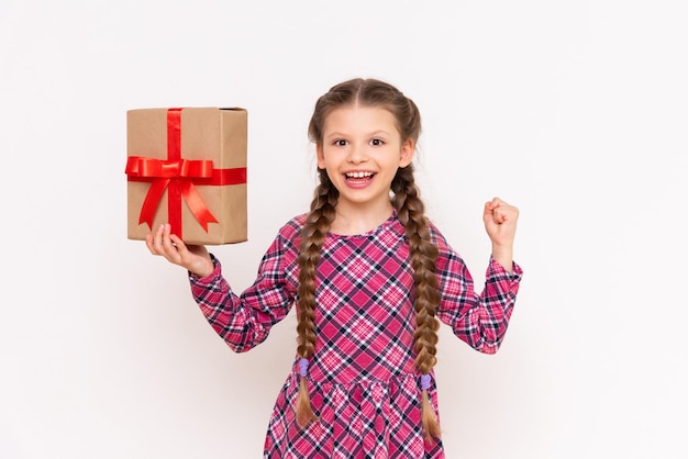 The girl holds a large gift box with a red bow and smiles broadly Birthday concept white isolated background