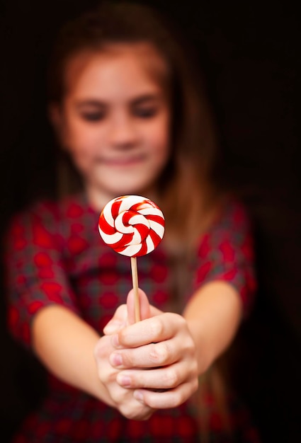 girl holds out a Christmas lollipop. focus on lollipop