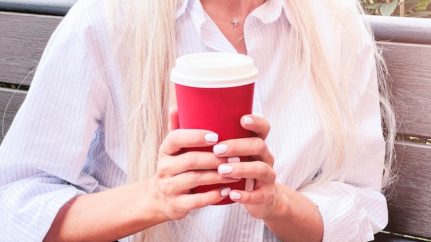 The girl holds paper coffee cup in hands Takeaway coffee concep