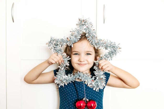 A girl holds a star in her hands to decorate the house for the new year and Christmas, the child is preparing for the holiday, helping parents, waiting for gifts