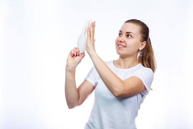 The girl holds white medical gloves in her hands. Protection against germs and the virus. She is in a white T-shirt on a white background.