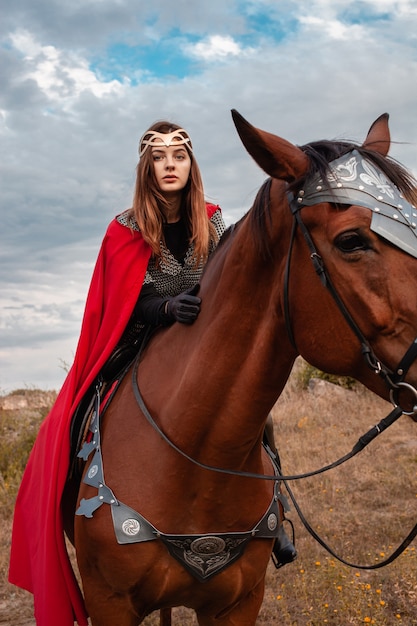 A girl on horseback against the sky. A beautiful woman in the costume of the warrior queen.