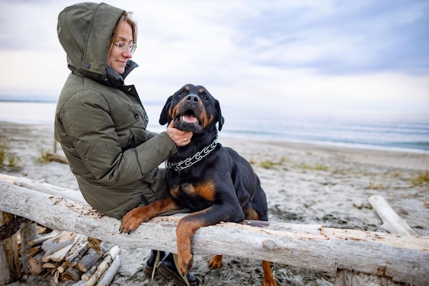 Girl hugging a Rottweiler dog on the beach