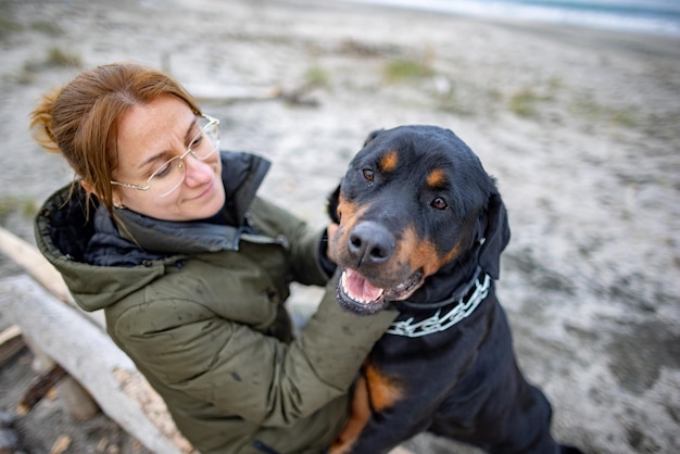 Girl hugging a Rottweiler dog on the beach