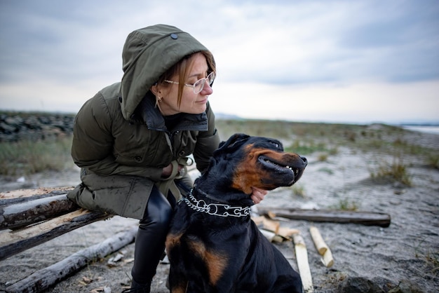 Girl hugging a Rottweiler dog on the beach