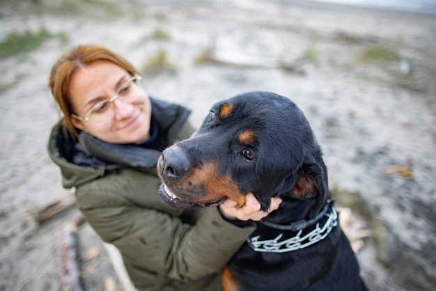 Girl hugging a Rottweiler dog on the beach