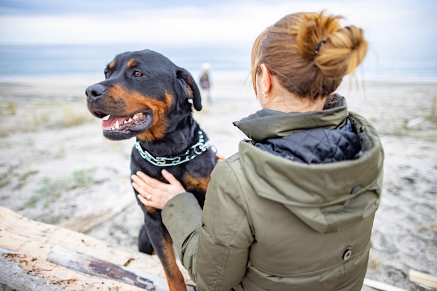 Girl hugging a Rottweiler dog on the beach