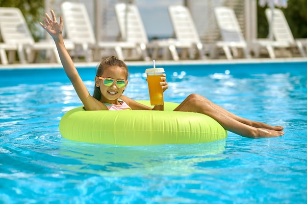 Girl on inflatable circle on water gesticulating in greeting