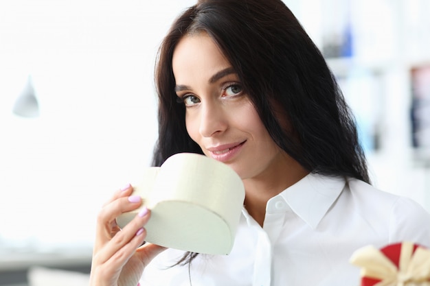 Girl inhales fragrance from gift in form heart