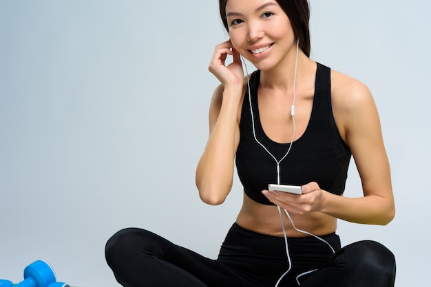 Girl inserts the earphone in her ear so that the case.