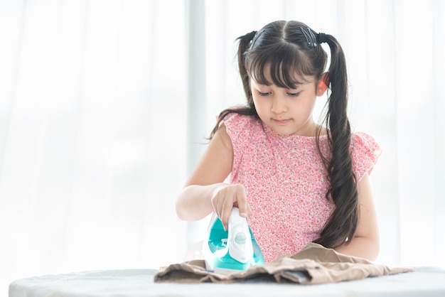 girl iron her school uniform with iron on iron board at home during weekend activity