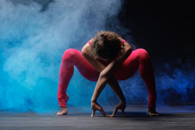 The girl is engaged in fitness and yoga on a dark background a stylish photo of fitness and yoga