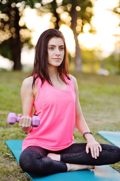 The girl is engaged in sports or fitness and holds in hands a pink bottle with water or a protein cocktail.