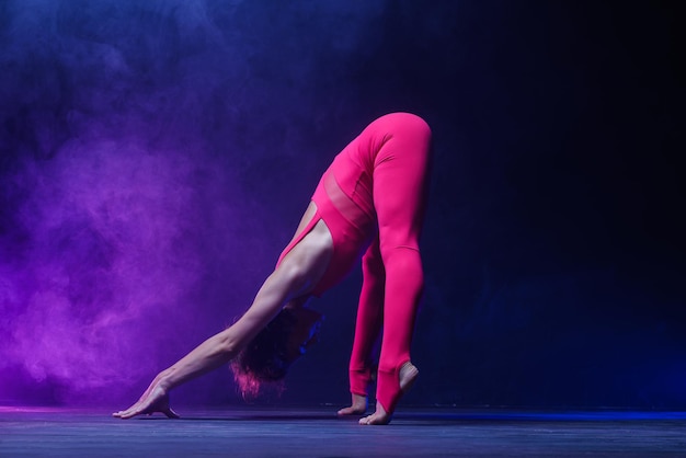 The girl is engaged in stretching on a dark background a stylish photo of fitness and yoga