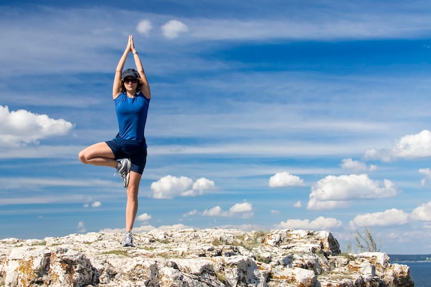 The girl is engaged in yoga on a background of cloudy sky tree pose