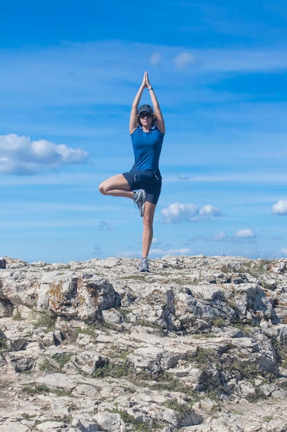 The girl is engaged in yoga on a background of cloudy sky tree pose