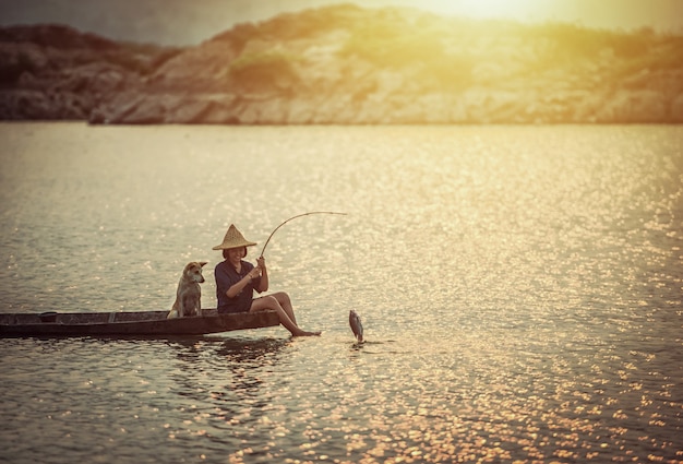 Girl is fishing on boat with her dog