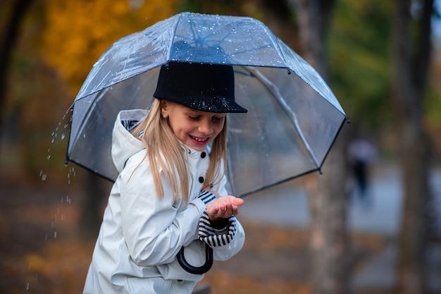 The girl is hiding from the rain under an umbrella. Autumn Park