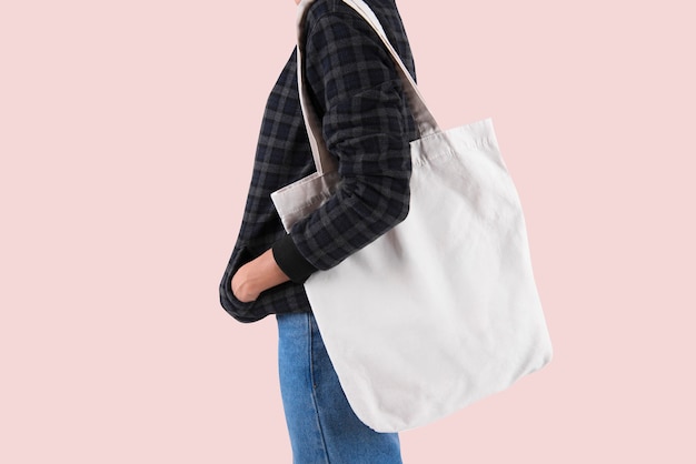 Girl is holding bag canvas fabric for mockup blank template isolated on gray background.