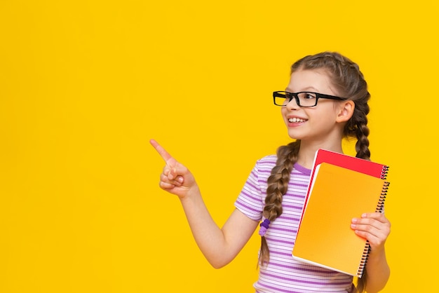 The girl is holding a book and looking away Cute little girl on yellow isolated background