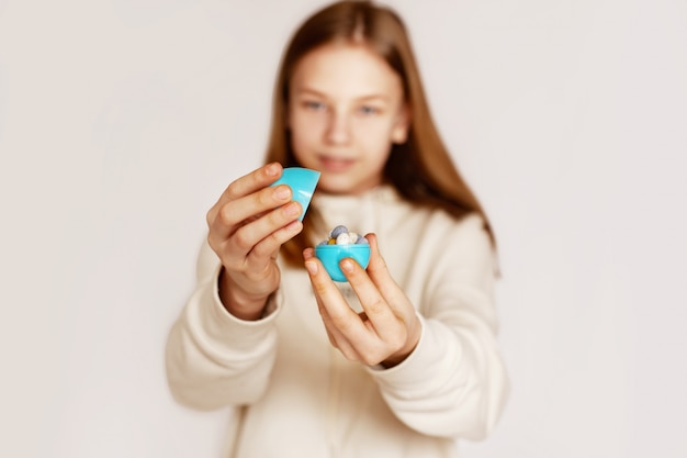 The girl is holding small chocolate eggs lying in one large egg