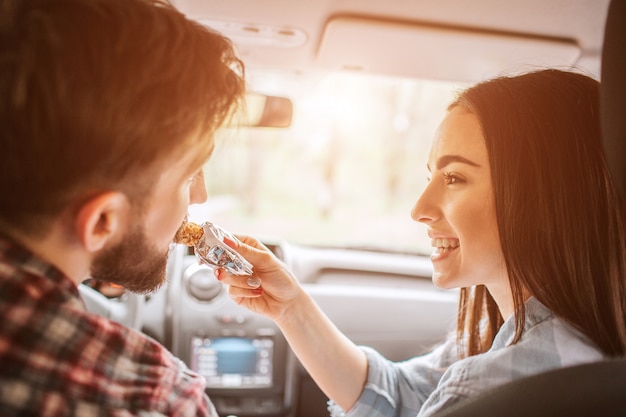 Girl is holding a sweet bar and feeding it to her boyfriend