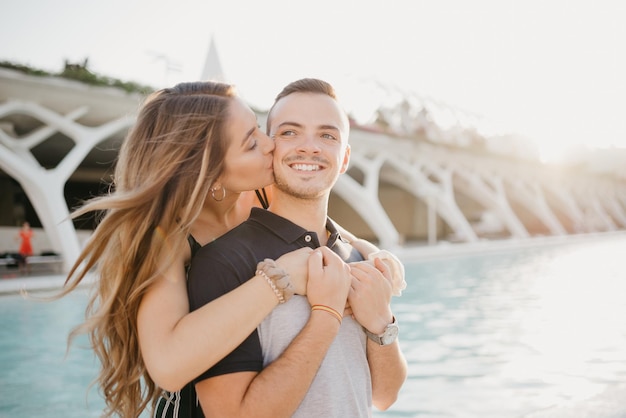 A girl is hugging her boyfriend from the back in the modern urban space in Spain