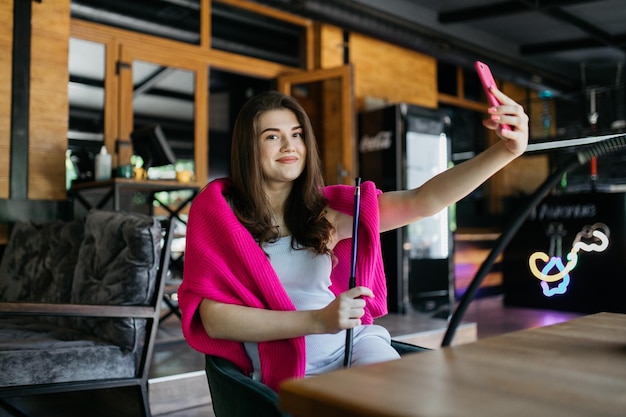 The girl is photographed in a cafe and smokes a hookah Girl in a cafe smokes a hookah The girl is sitting in a cafe