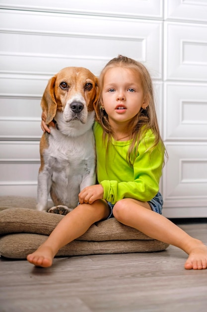 Girl is sitting on floor in house with pet in an embrace