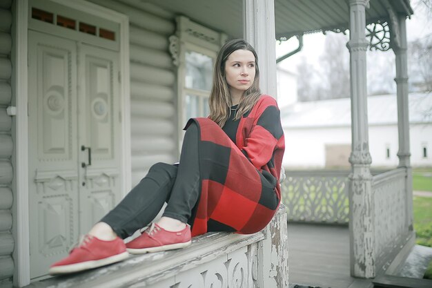 girl is sitting on a garden bench / beautiful model posing sitting in  coat on  bench in  city park, beautiful girl