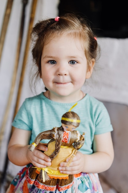 The girl is standing and holding a doll