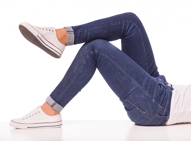 Girl in jeans lies on a white floor.