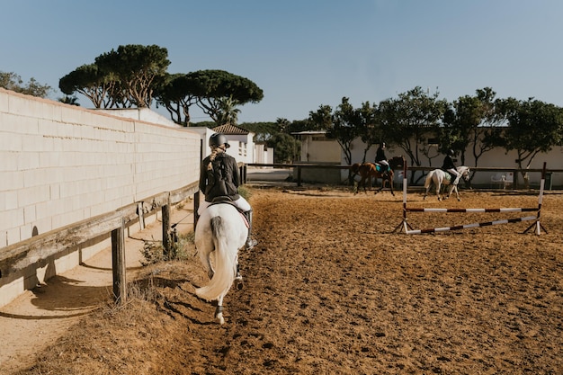 Girl jogging a white horse around an equestrian arena