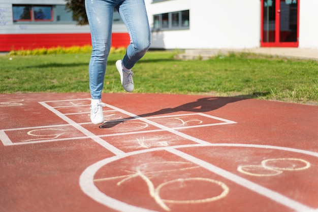 Girl Jumping while Playing Hopscotch at park Girls on Children Playground outdoors