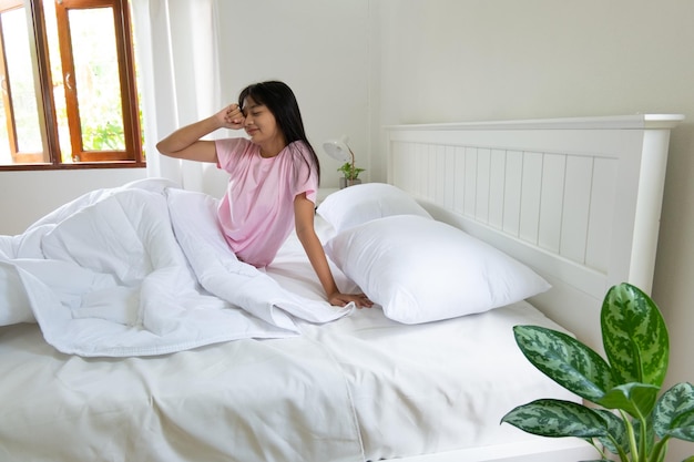 The girl just waking up and sitting on the bed