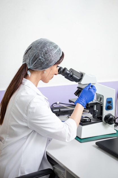 Girl lab technician works on a microscope