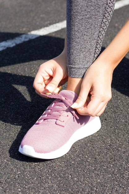 Girl lacings on his Pink sneakers for running no face closeup Outdoors sunlight stadium sport and fitness concept