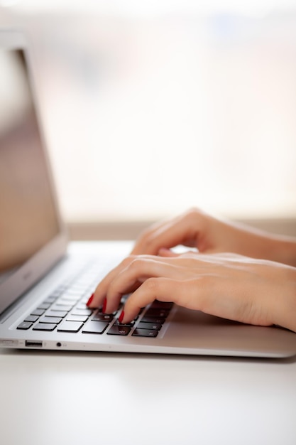 The girl behind the laptop. Female hands typing text on the keyboard while exchanging messages