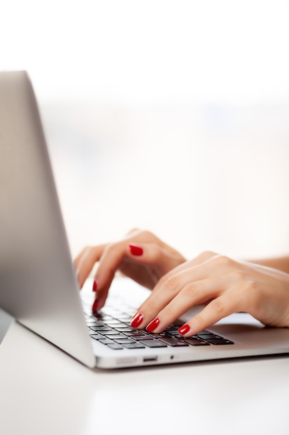 The girl behind the laptop Female hands typing text on the keyboard