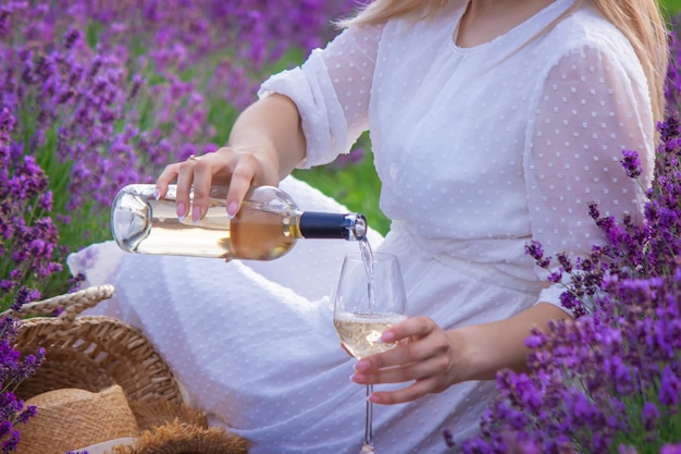 A girl in a lavender field pours wine into a glass Relaxation