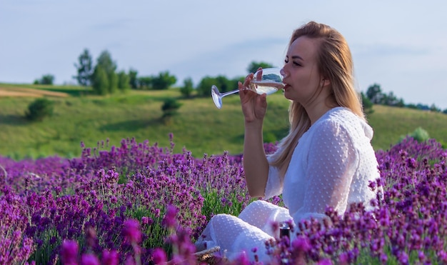 A girl in a lavender field pours wine into a glass Relaxation