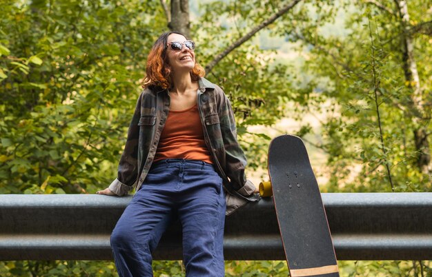 Girl leaning on fence next to skateboard