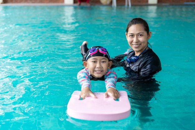 Girl learning to swim with coach at the leisure center