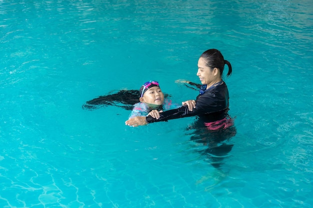 Girl learning to swim with coach at the leisure center