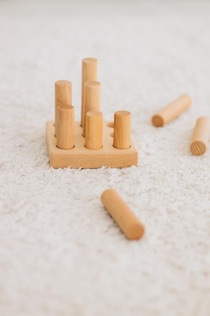 The girl learns colors by playing with wooden cylindrical toy colored human figures and placing them in cups of the appropriate color The child is happy that he completed the task correctly