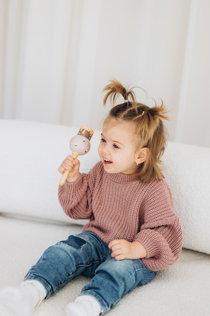 The girl learns colors by playing with wooden cylindrical toy colored human figures and placing them in cups of the appropriate color The child is happy that he completed the task correctly