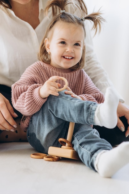 The girl learns colors by playing with wooden cylindrical toy colored human figures and placing them in cups of the appropriate color The child is happy that he completed the task correctly